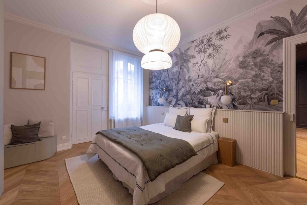 Tête de lit avec revêtement Orac Decor, papier peint panoramique et interrupteurs en laiton brossé.