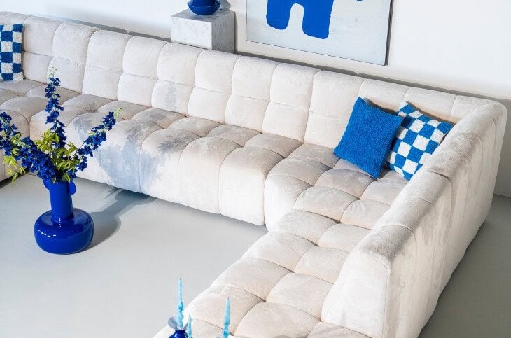 Canapé de la marque drawer dans un velours crème accompagné de coussins et décorations bleus