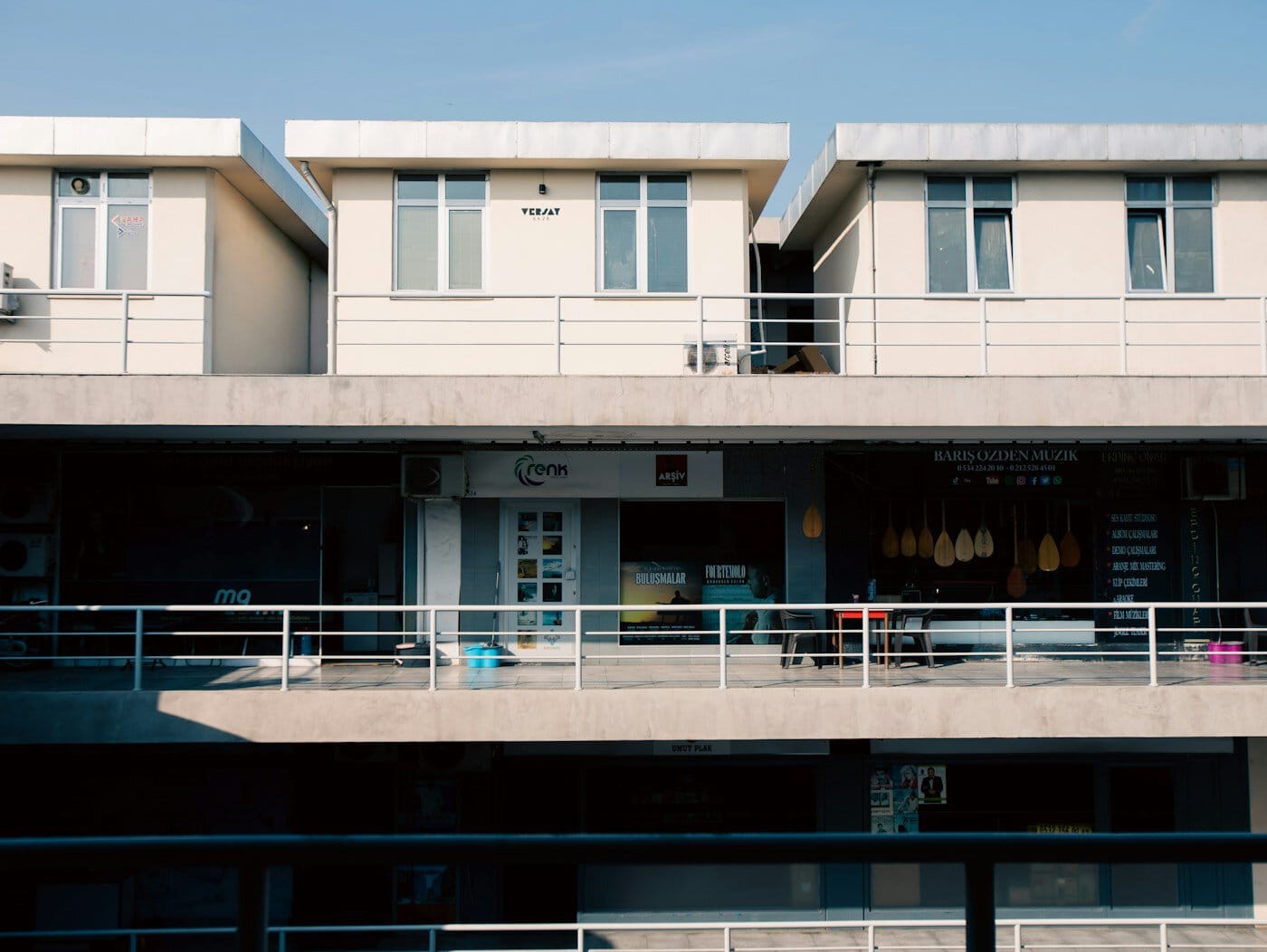 Row of modern buildings with balconies and shops.